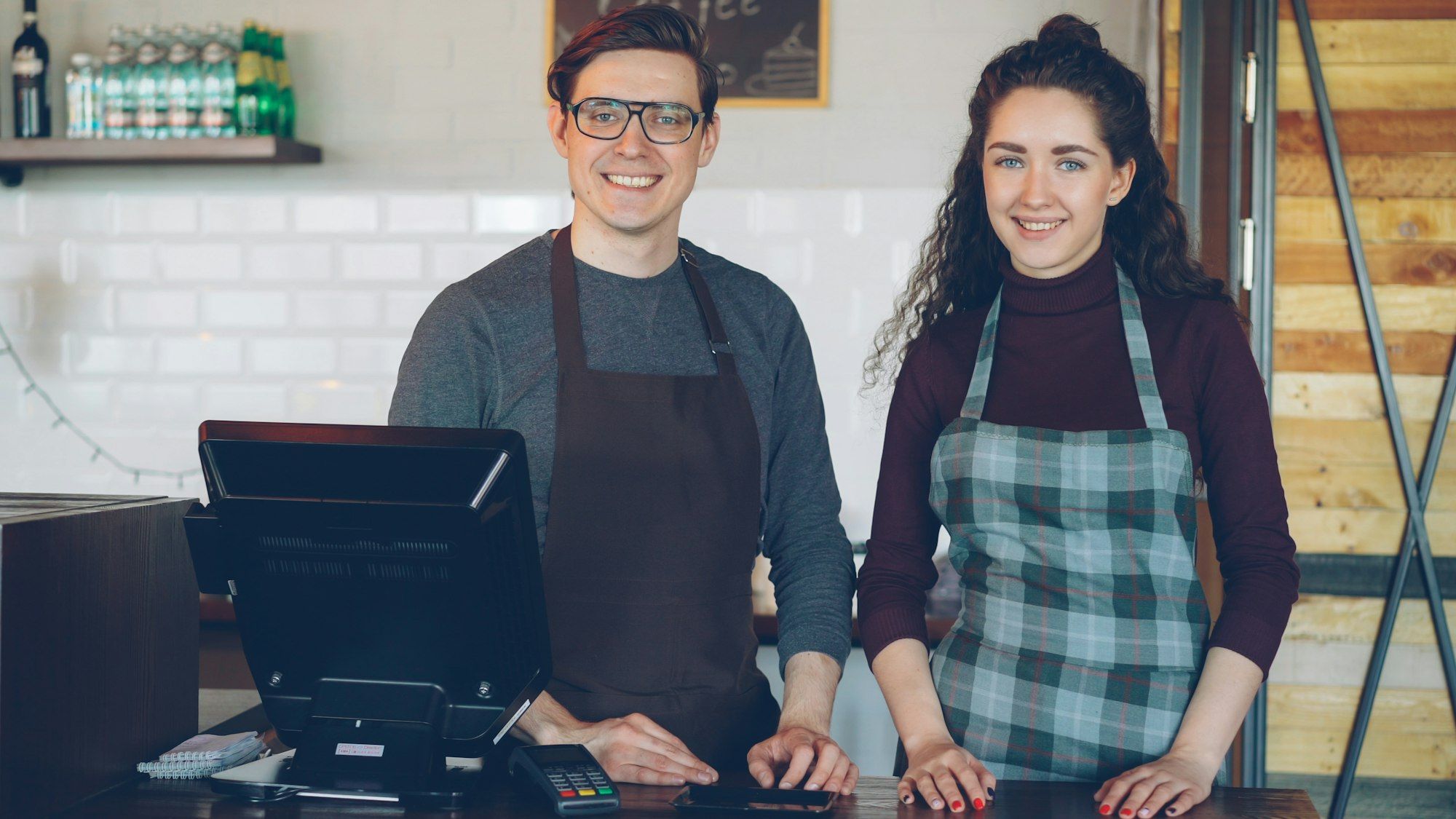 Two smiling cafe owners standing behind their counter