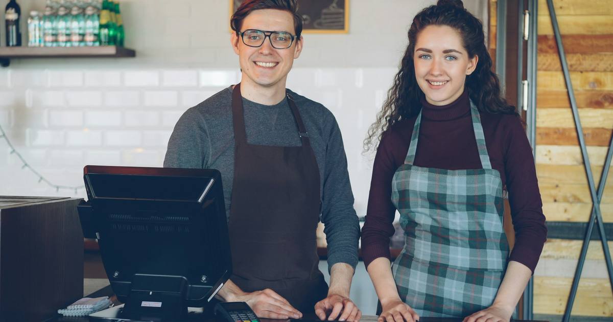 Two smiling cafe owners standing behind their counter
