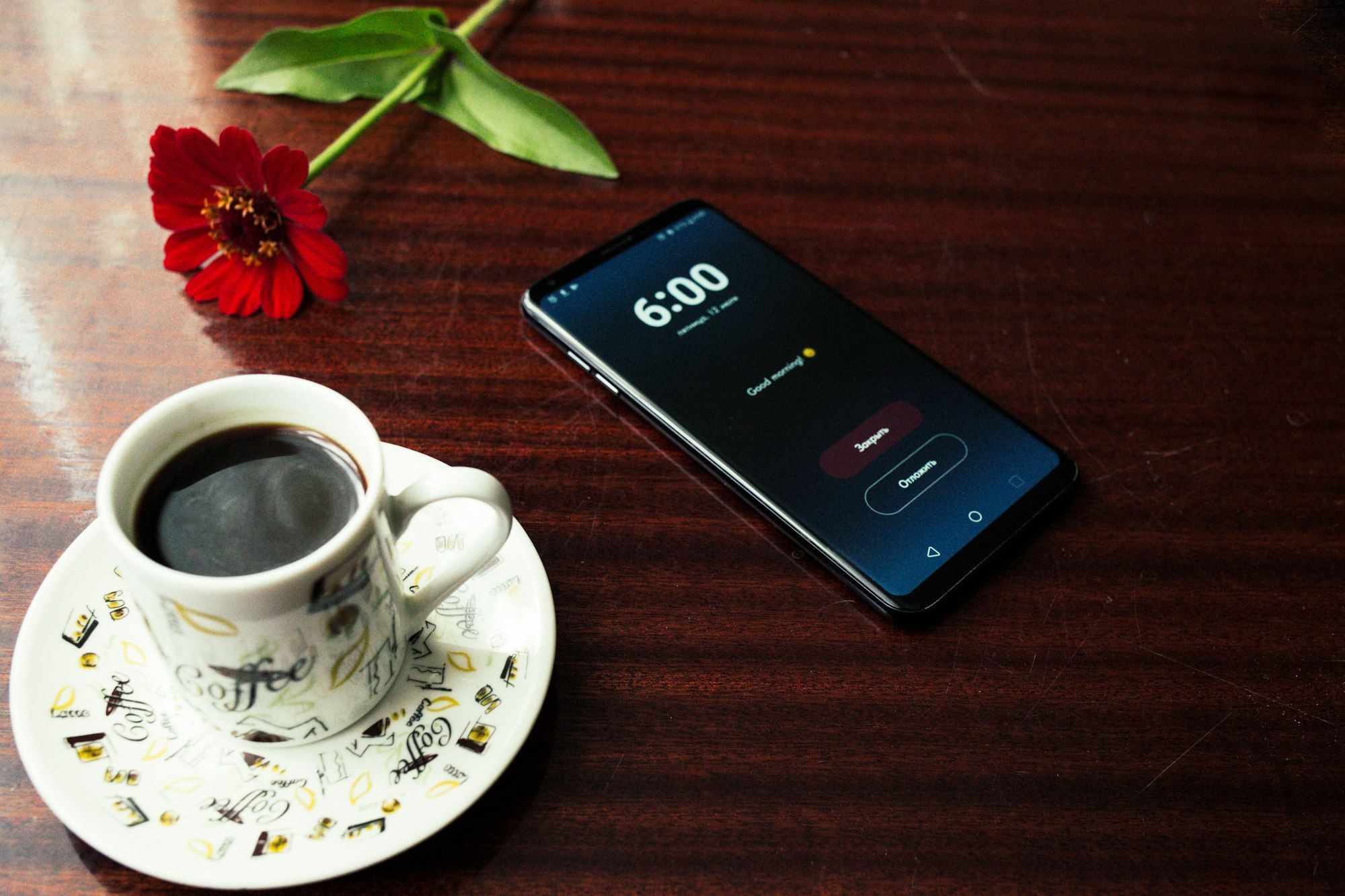 A smartphone next to a cup of coffee on a table