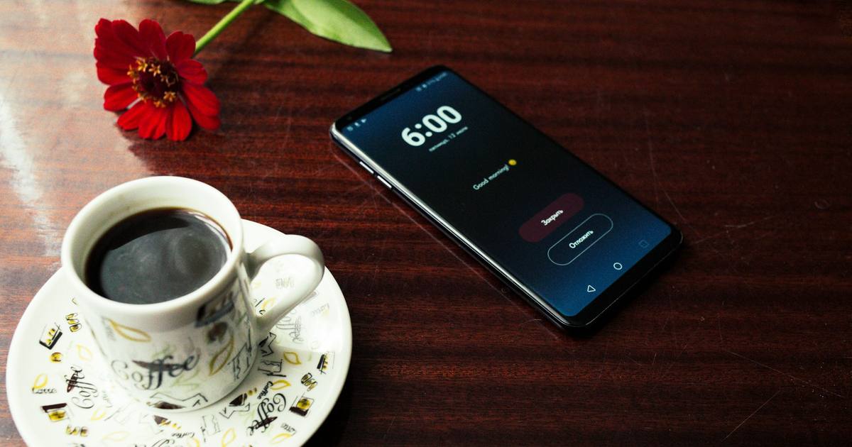A smartphone next to a cup of coffee on a table