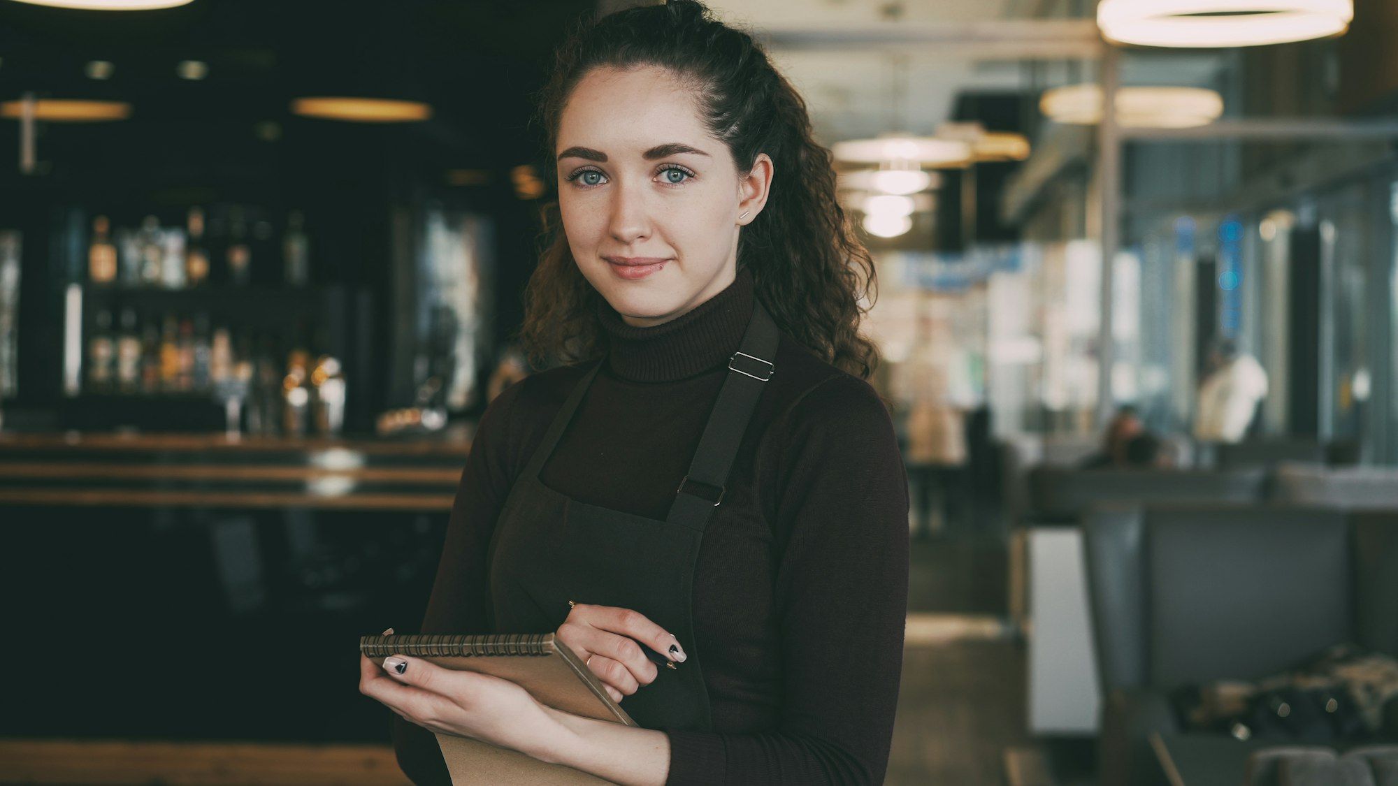 A small business owner in an apron holding a tablet