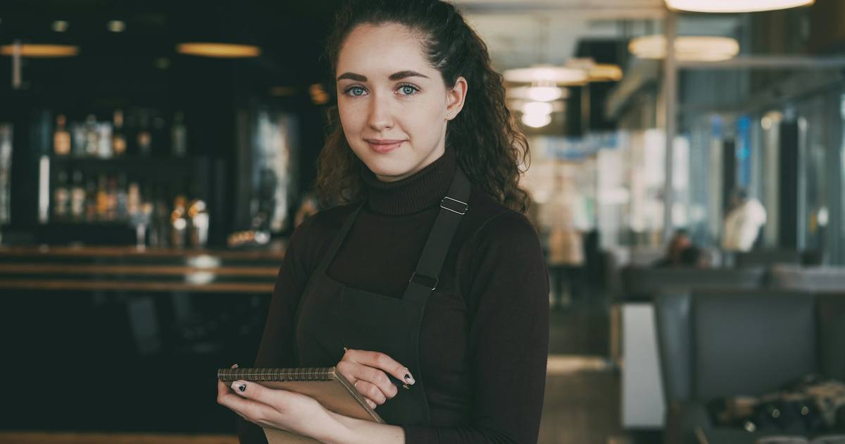 A small business owner in an apron holding a tablet