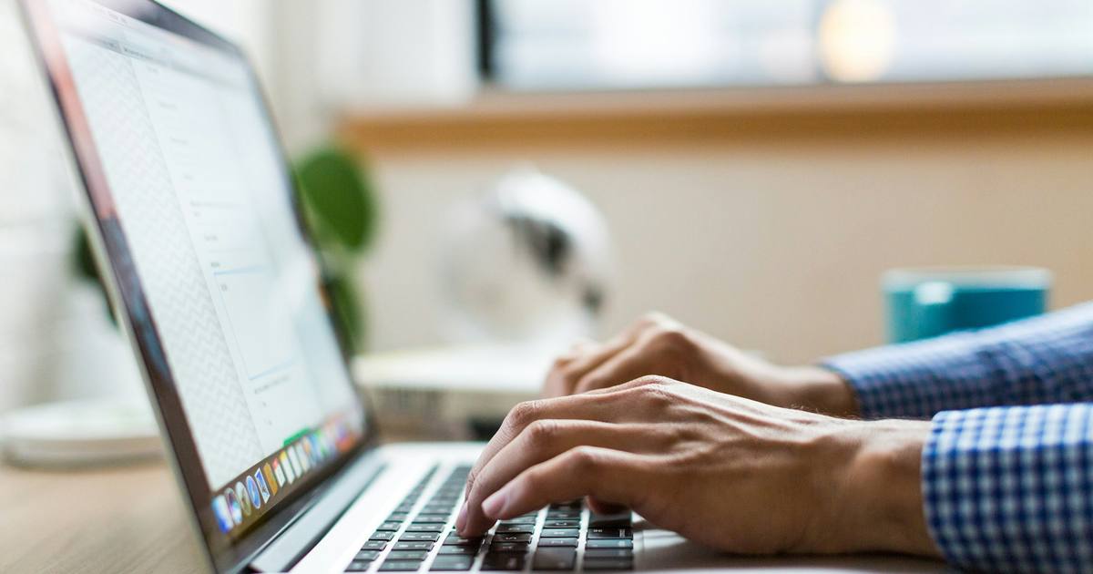 Hands typing on a laptop keyboard