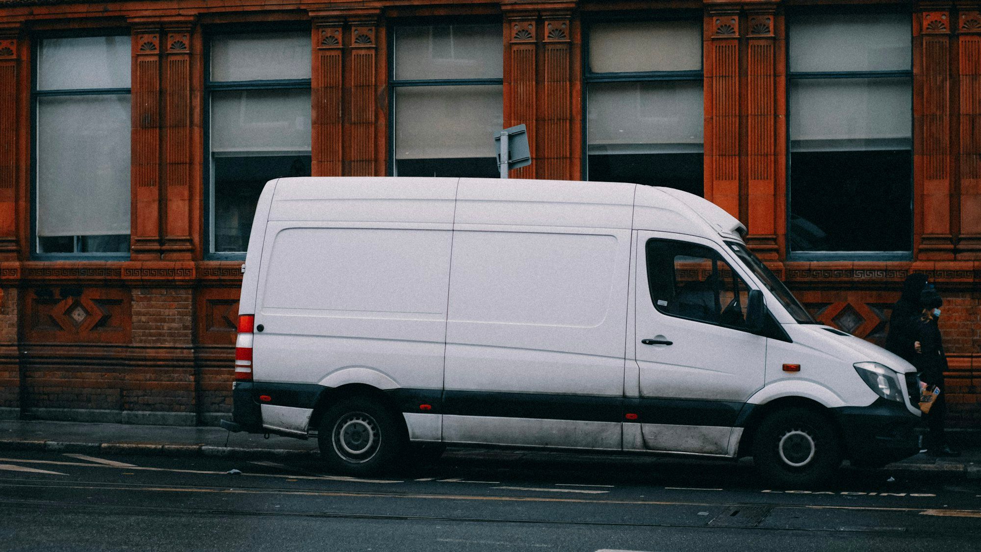 A white work van parked at the side of a street