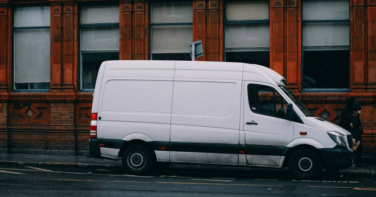 A white work van parked at the side of a street
