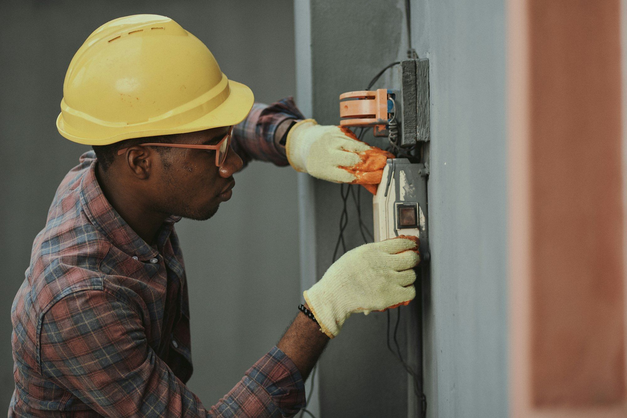 An electrician in a yellow hard hat working on wiring